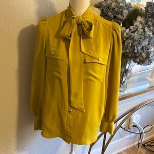Express gold colored blouse with a tie neck,  with gold button detail. Sz L